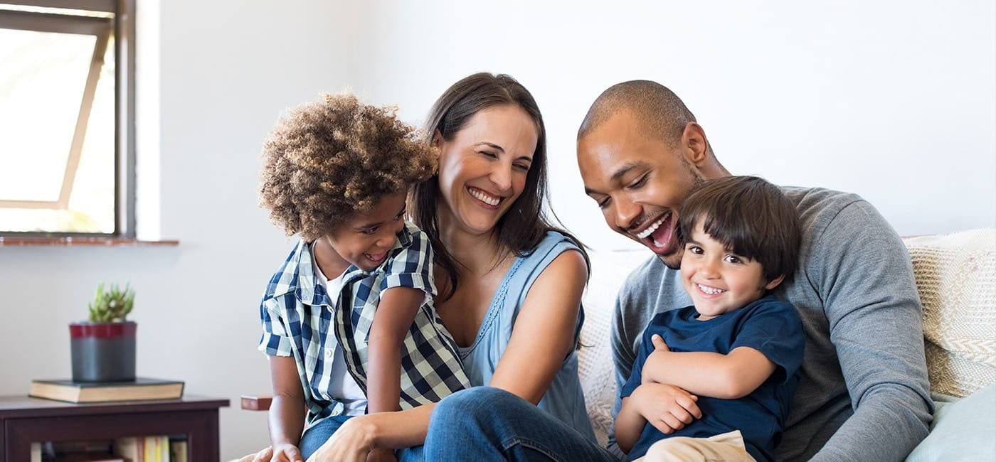 Smiling family of four sitting on couch