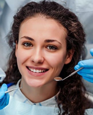 young woman with curly hair smiling in the dental chair