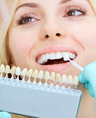 woman checking veneers against smile with her cosmetic dentist