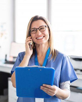 dental team member talking on the phone and holding a clipboard 