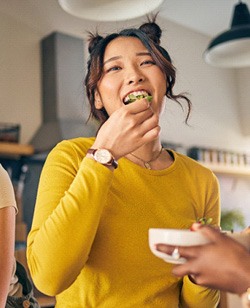 Woman in yellow shirt eating meal with friends