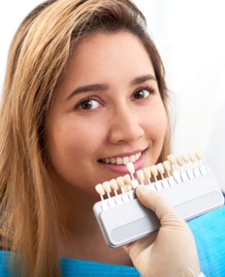 cosmetic dentist in Federal Way holding a row of veneers to a patient’s smile