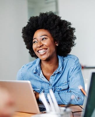 person smiling and sitting down at work at their desk