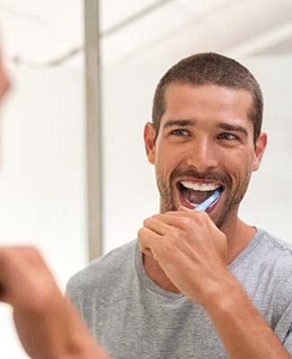 man brushing his teeth in front of a mirror