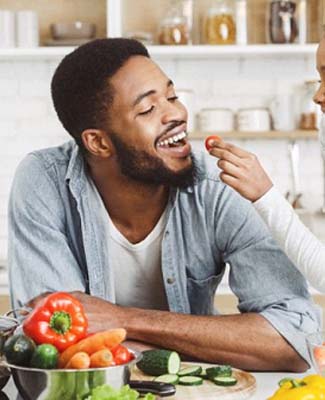 small child giving their dad a cherry tomato