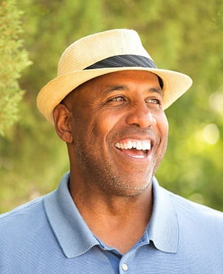 older man smiling and wearing a fedora