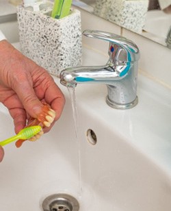 Person cleaning dentures in Federal Way   