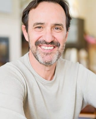 Man in grey shirt smiling with dentures in Federal Way