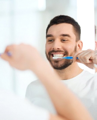 man brushing his teeth in front of a mirror