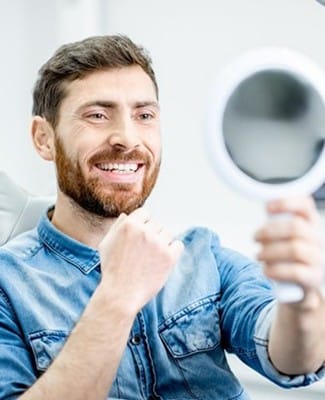 man admiring his smile in a mirror 