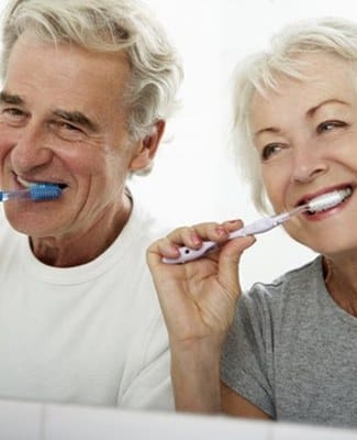 elderly couple brushing their teeth together 