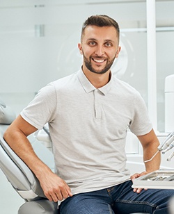 Man in grey polo and blue jeans sitting upright in the dental chair