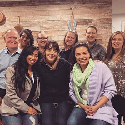 Federal Way dentist and dental team members smiling in front fo wooden wall