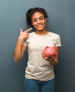 young woman pointing to her smile and holding a piggy bank