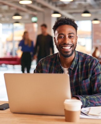 Man smiling while working on laptop in office