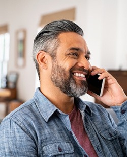 Man smiling while talking on phone at home