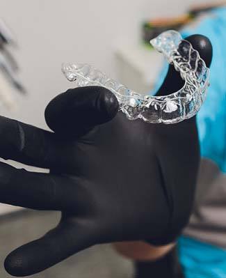 Dentist in Federal Way holding up Invisalign aligner