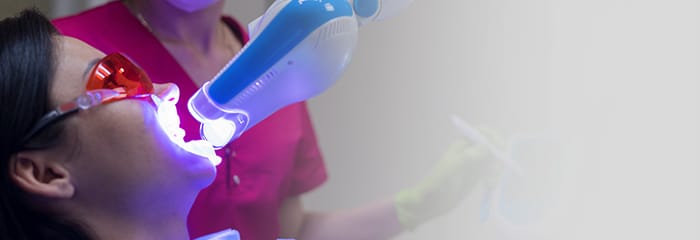 Woman getting her teeth whitened in dental office