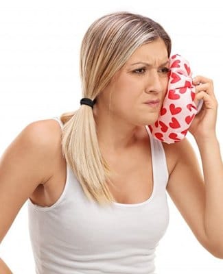 woman applying cold compress to face