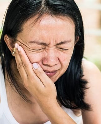 woman holding her mouth in pain