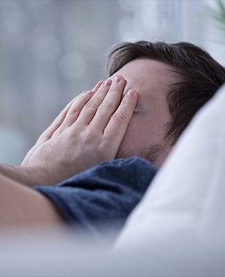 man in bed covering face