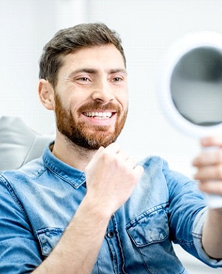 dental patient admiring his smile in a mirror