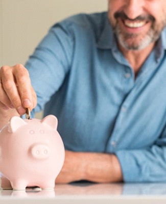 man putting coins into a pink piggy bank