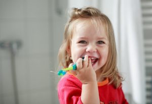 little girl smiling with a toothbrush