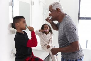 parent and children brushing their teeth together