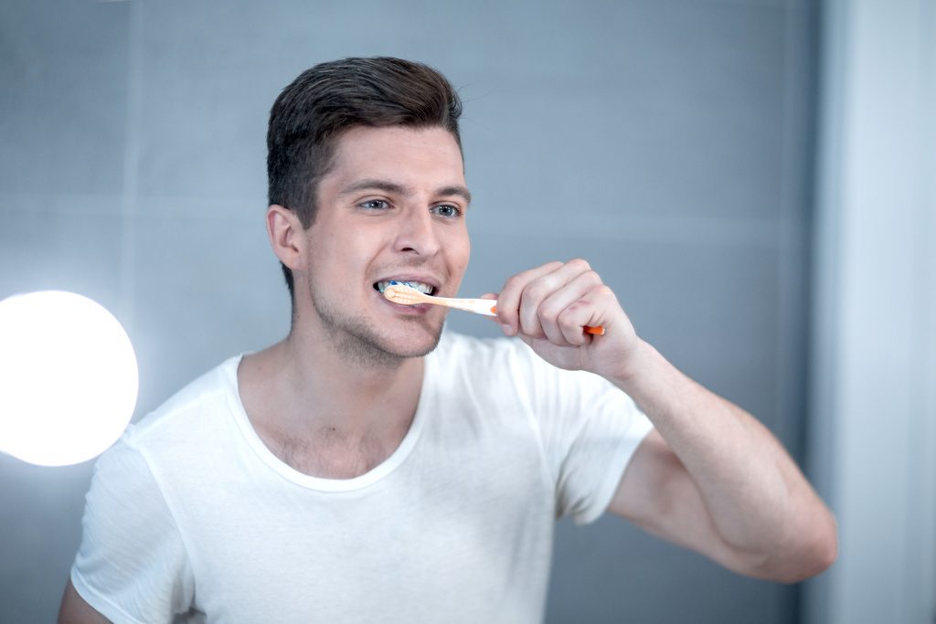 Young man uses a toothbrush to keep his teeth clean and healthy.