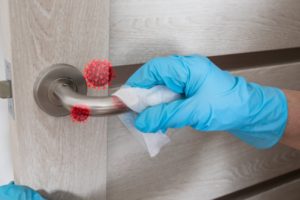 dentist sanitizing the door handle of their dental practice