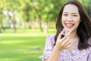 Woman smiling and holding her Invisalign aligner