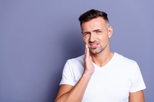 a man experiencing facial pain due to a dental emergency