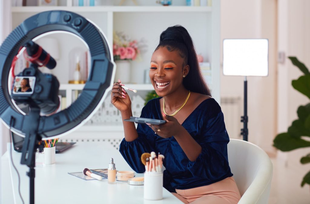 Woman smiling while recording makeup video in studio